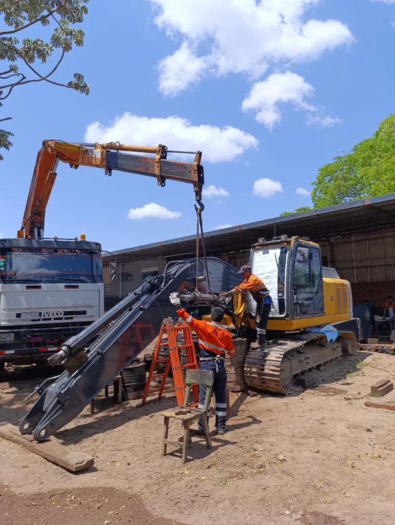 Técnicos realizando el montaje del brazo de una excavadora con soporte de camión grúa